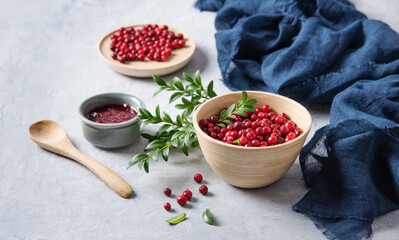 juicy forest lingonberry with handmade jam  in a wooden bowl on white table with blue napkin. Concept homemade healthy food. Close up
