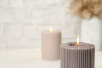 Fototapeta na wymiar Burning candle on blurred background, closeup. Space for text