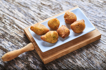 Grupo de buñuelos sobre una mesa de madera rústica y presentados para comer, con colores neutros.