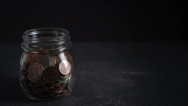 Concept of Investment and Savings Growth and Loss, Timelapse of New Zealand Coins Filling Up a Glass Jar and then Emptying Again on a Dark Background with Copy Space