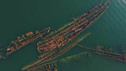 Wrecks of sunken metal ships in the sea. The tops, which protruded from the water, were cut by...