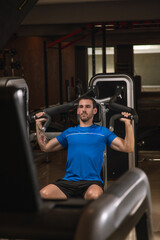 young man exercising lats on machine