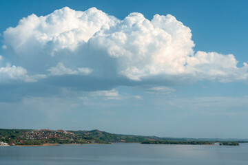 group of white cumulus clouds on blue sky over hilly river bank as natural background