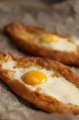 two Adjarian khachapuri with egg yolk on top on baking paper