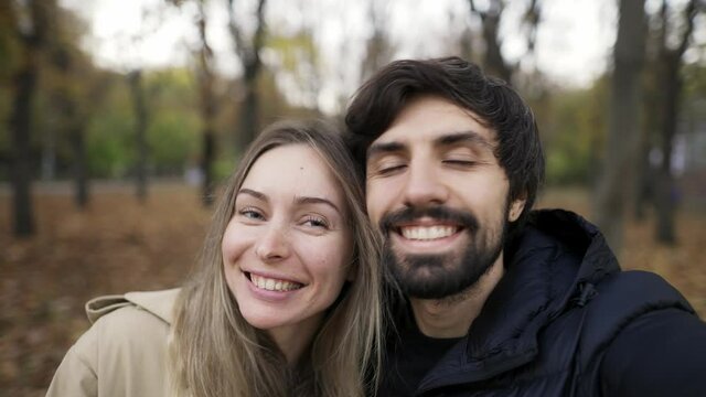 Cute couple making selfie on a bench in the park at autumn fall season