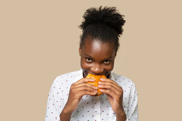Young african female eats delicious burger 