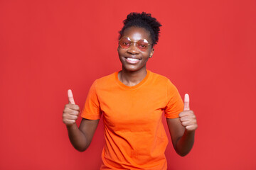 beautiful young female in glasses with hand gesture on red background 