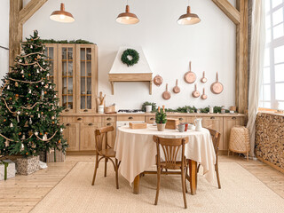 Fototapeta na wymiar Modern, light, festive, cozy kitchen interior with Christmas and New Year decorations, kitchen table, utensils, copper pans on wall and big Christmas tree with presents, winter holidays concept