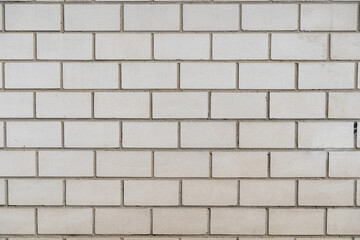 Grey brick wall background texture. Multiple rows of weathered stone blocks. Full frame backdrop of a building facade. Rough exterior of a house in aged condition.