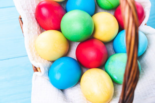basket with colorful Easter eggs on a blue wooden background, selective focus, tinted image