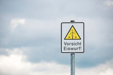 Ein Hinweisschild, das vor Eiswurf von nahegelegenen Windrädern warnt