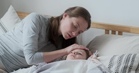 Closeup caring mother touching hot forehead of son checking body temperature worried about health. Unwell male kid lying under warm plaid feeling chill with influenza seasonal viral infection disease