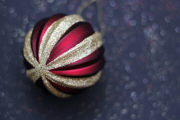 Naklejka premium Golden-red Christmas tree ball on a dark background with bokeh.