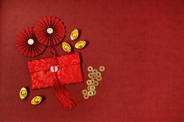 Chinese new year festival decoration over red background. traditional lunar new year red pokets, gold ingots, coins. Flat lay, top view