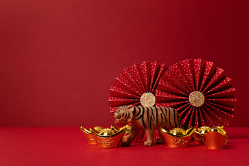 Chinese new year festival decoration over red background. traditional lunar new year gold ingots, paper fans, tiger. Copy space - obrazy, fototapety, plakaty