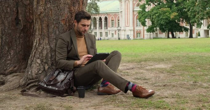 Harvard Business School. startup Businessman working in tablet to find solution. Student sit outside on Quad lawn of University of Illinois college campus in Urbana Champaign. University Campus
