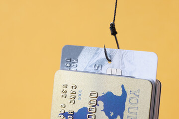 Lot of bank cards hanging on fishing hook on yellow background closeup