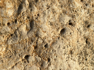 texture of the wall is made of yellow sandy crumbly rock of rock with shards and layers. The background