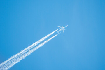 Ein Flugzeug mit Kondensstreifen vor strahlend blauem Himmel