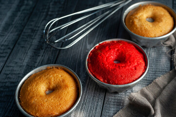 vanilla and red velvet puddings with powdered sugar with strainer and whisk on wooden table and plate and window light