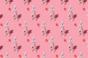 pattern from human skeleton holds a red headache pill in its hands. A trending image on a pink background for the Halloween celebration. Conceptual image about the dangers of medicines.
