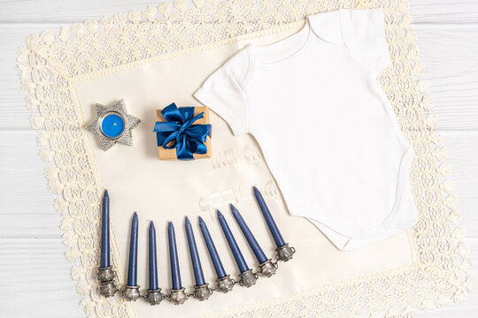 Jewish holiday Hanukkah white romper mockup with menorah, gift box and candles, Top view from above on white background. Flat lay, copy space.