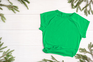 Green t-shirt mockup with copy space, Christmas Holiday template flatlay. Top view blank t-shirt on white background. Happy New Year decorations