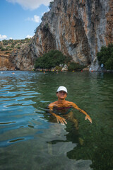 Woman in a white cap covered with fish peeling at the Voulagmeni thermal lake, Greece