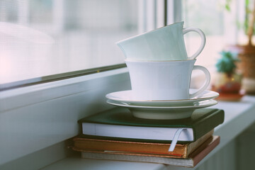 Composition of two porcelain tea cups with saucers on the windowsill. Selective focus.