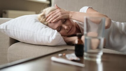 Sick sad woman lies on the couch at home. A middle-aged caucasian unhealthy woman is lying on a sofa , she feeling bad, headache, illness, need a rest and treatment