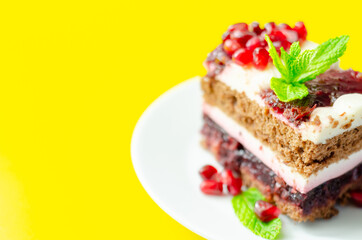 Colorful layered cream chocolate cake with cherry jam and pomegranate