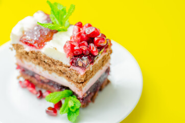 Colorful layered cream chocolate cake with cherry jam and pomegranate