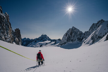 Alpinist or climber on glacier in mountain alpine landscape of Chamonix, France. Mountaineering in snow covered mountains of Mont Blanc. Ascent on a glacier with a rope and ice axe. Winter adventure.