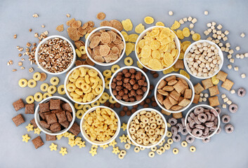 Various breakfast cereals on light grey background, assorted corn flakes in bowls, quick food for kid breakfast