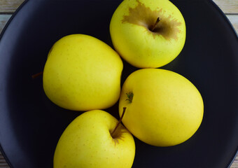 Top view. Yellow apples on dark plate.
