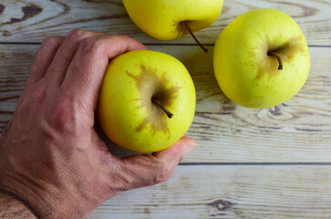 Picking a yellow apple on a rustic wooden table. Top view and copy space.