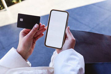 Close up of female hands holding credit card mockup and blank phone screen on the street, online shopping, place for your text