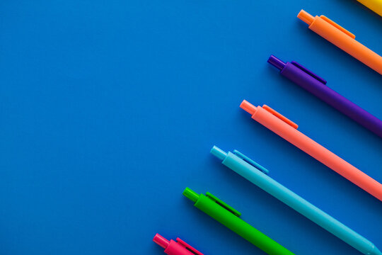 Row of Multicolored Pen Tops on Blue