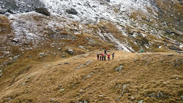 Aerial drone view of nature in Romania. Transfagarasan route in Carpathian mountains, group of tourists taking photos near rocky slopes covered with snow