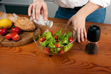 Close up of female hands salting salad in the kitchen
