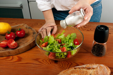 Close up of female hands salting salad in the kitchen