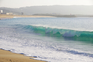A turquoise wave breaking at Nazare beach, Portugal