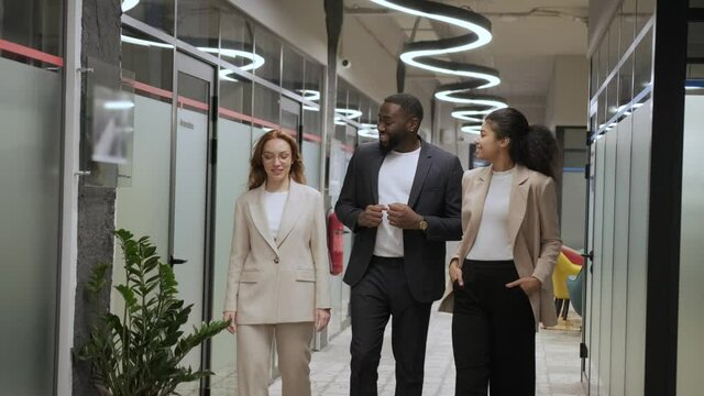 stylish employees in business suits walk in the office and communicate amicably. International team
