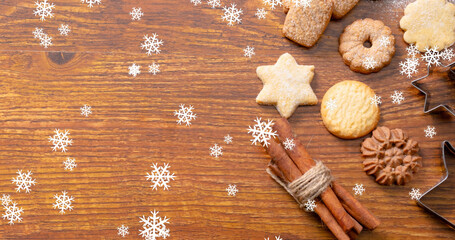 Image of snow falling over christmas cookies on table