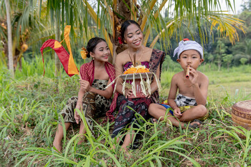 Balinese girl and boy playing whistle in rice fields. 