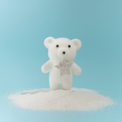 A small polar bear in the snow on a pastel blue background. Minimal creative New Year's concept.