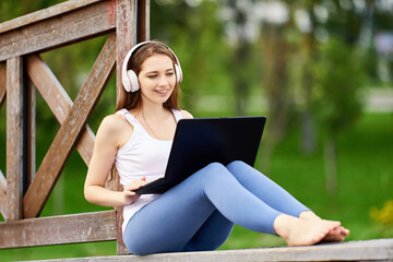 Online learning or teleworking using laptop connected internet via 5g network, young woman does e-learning while visiting public park.