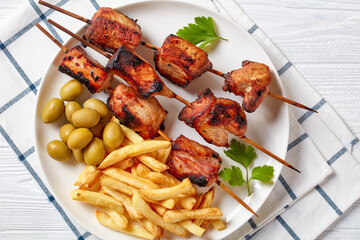 grilled pork kebabs with potato fries on a plate