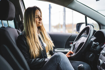 Fototapeta na wymiar Young adult one caucasian woman sitting in car waiting side view copy space