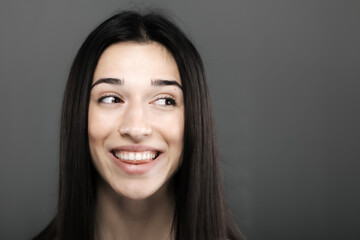 studio portrait of a beautiful young girl against gray backgroung. looking aside.